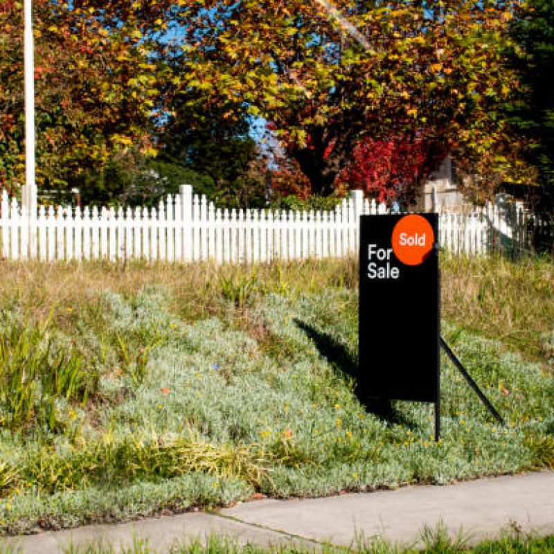 For sale sign near the residential building house with 'SOLD' sold sticker on it. Auction clearance rate